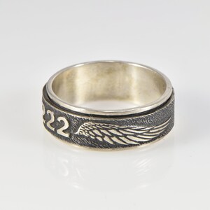 May include: A silver ring with a spinning band featuring a wing design and the number "22" engraved on the side.