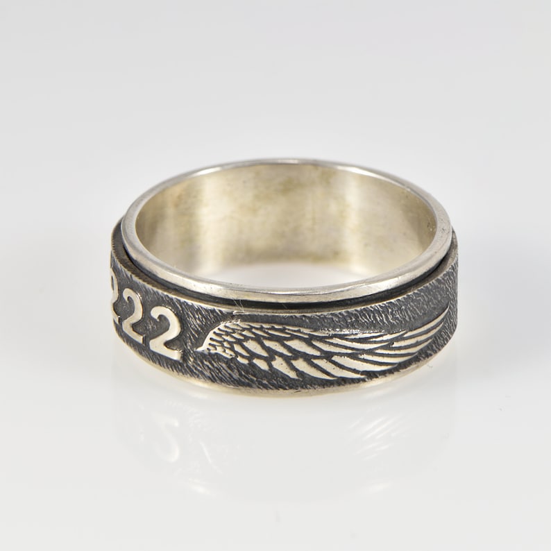 May include: A silver ring with a spinning band featuring a wing design and the number "22" engraved on the side.