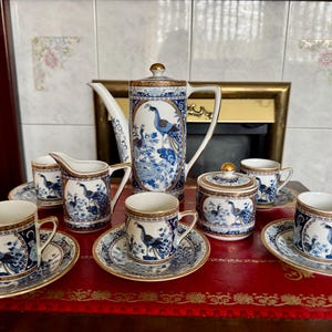 Puede incluir: Juego de té de porcelana con diseño de pavo real azul y blanco. El juego incluye una tetera, una cremera, un azucarero, seis tazas y platillos. Los bordes y las asas están adornados con oro.