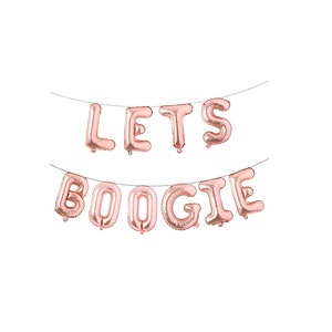 May include: A set of rose gold foil letter balloons strung on a thin wire, spelling out the phrase LETS BOOGIE. The balloons have a metallic finish and are arranged in two separate rows, with LETS on the top line and BOOGIE on the bottom line.