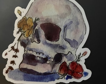 May include: A watercolour painting of a human skull with yellow and red flowers. The skull is painted in shades of grey and blue, and the flowers are painted in vibrant colours.