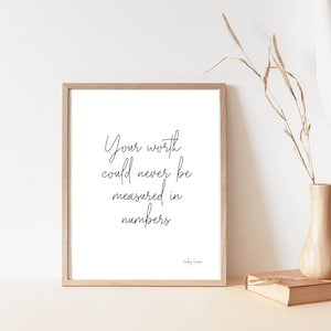 May include: A black and white printable quote in a wooden frame. The quote reads "Your worth could never be measured in numbers." -  Audrey Hepburn.
