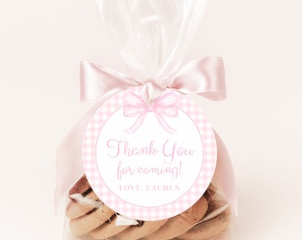 Könnte beinhalten: Eine rosa und weiße Gingham-Geschenkstüte mit einem runden Etikett, auf dem "Vielen Dank für's Kommen! Liebe, Lauren" steht. Das Etikett ist mit einer rosa Schleife verziert.