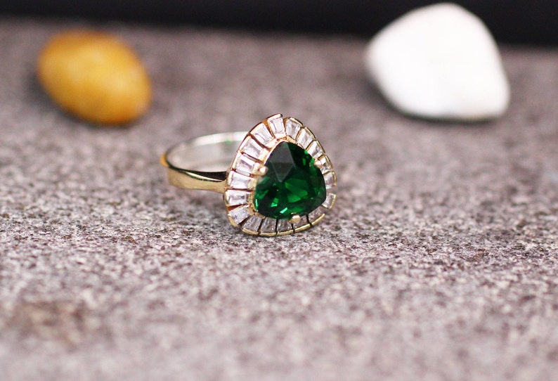 May include: A silver ring with a large green pear-shaped gemstone surrounded by smaller clear gemstones.