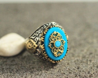May include: A silver ring with a blue turquoise stone set in a gold filigree design.