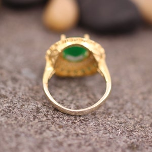 May include: A gold ring with a green gemstone set in a filigree design.