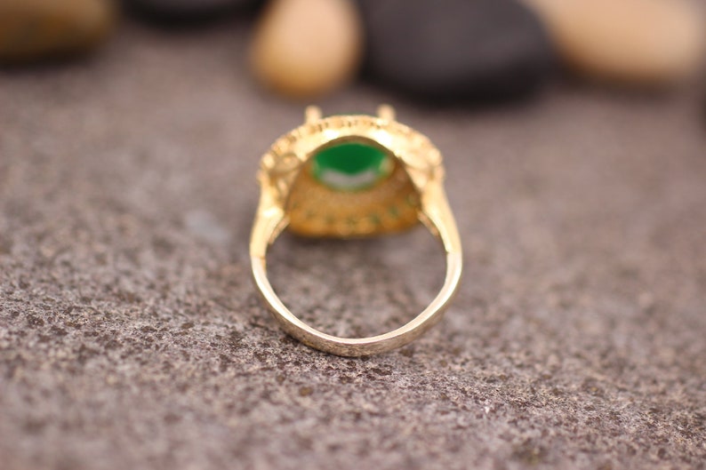 May include: A gold ring with a green gemstone set in a filigree design.