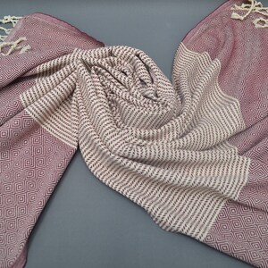 Pu&ograve; includere: Un asciugamano turco con frange di colore bordeaux e crema. L'asciugamano &egrave; realizzato in cotone e ha una texture morbida e assorbente.