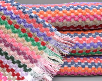 May include: A stack of colorful towels with a geometric pattern. The towels are made of a soft, fluffy material and have a fringe trim.