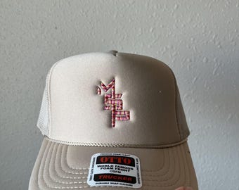 Könnte beinhalten: Ein beiger Trucker-Hut mit einem gestickten Logo in Pink und Rot. Der Hut hat ein Netzrücken und ein Etikett mit der Aufschrift "OTTO World Famous Foam Front OSFM Trucker Durable Snap Closure".