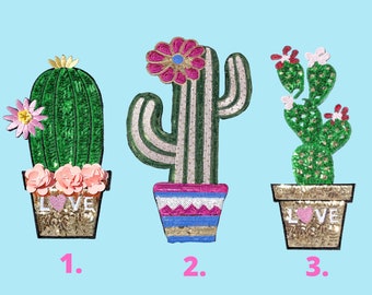 May include: Three embroidered cactus patches with sequins. The first cactus is green with pink flowers and the word "LOVE" on the pot. The second cactus is green and white with a pink flower and a pink, blue, and white striped pot. The third cactus is green with pink flowers and the word "LOVE" on the pot.
