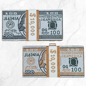 May include: Two rectangular clutches designed to resemble stacks of $100 bills. The clutches feature a beaded design with details like the serial number, the words "United States of America", and the number "100".
