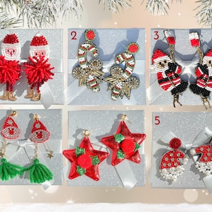 May include: Six pairs of Christmas-themed earrings displayed on white boxes with silver glitter. The earrings are made of beads, sequins, and pom-poms. The earrings feature Santa Claus, candy canes, stars, and Christmas trees.
