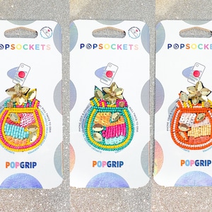 May include: Three colorful phone grips with a beaded design featuring a flower and a fruit. The grips are packaged on white cards with the text "POPSOCKET" and "POPGRIP".