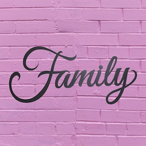 May include: The word "Family" is written in a black cursive font on a pink brick wall.