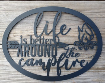 Könnte beinhalten: Schwarzes ovales Schild aus Metall mit dem Text "life is better around the campfire" und einem stilisierten Lagerfeuerbild.
