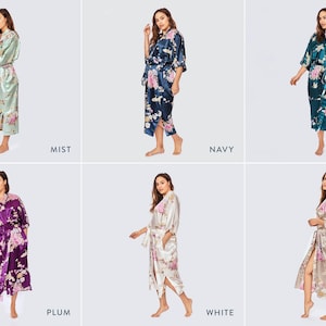 May include: A collection of six satin robes featuring the Chrysanthemum & Crane print in various colors including mist, navy, peacock, plum, white, and willow. Each robe has a tie waist, three-quarter length sleeves, and a floral pattern.