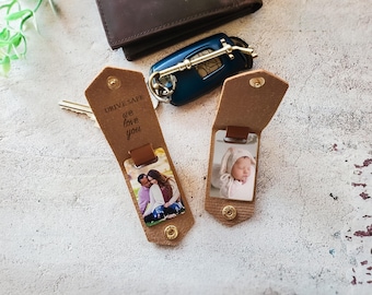 May include: Two brown leather keychains with photos, one open and one closed. The open keychain displays a photo of a couple, while the closed one shows a baby. The text "DRIVE SAFE we love you" is printed on the keychain.