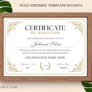May include: A printable certificate of donation template in Canva. The certificate is framed in a brown wood frame and has a gold border. The text reads "Certificate of Donation" and "This certificate is proudly given to Juliana Silva because on behalf of the name here has donated $5000 to the following charity/organization Organization Name Here". The date is September 1, 2024. The text "LOGO" is in a box with a gold wreath. The signature reads "Juliana Silva".