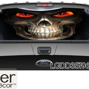 May include: A black pickup truck with a rear window decal of a skull with glowing orange eyes. The decal is of a skull wearing a hooded robe. The truck has a Ford logo and the text "LGDD351969-1" on the tailgate.
