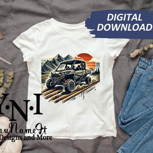 May include: White t-shirt with a graphic of a green and brown off-road vehicle driving through a mountain landscape. The text "Y.N.I. You Name It Designs and More" is printed on the bottom of the shirt.