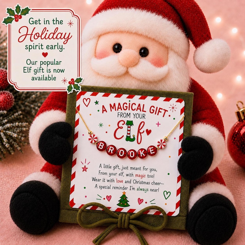 May include: A plush Santa Claus holding a square green gift box with a gold chain necklace featuring red and white beads spelling BROOKE. The card reads A MAGICAL GIFT FROM YOUR ELF and includes a poem about Christmas cheer and magic.