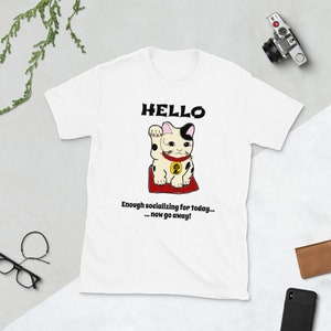 Puede incluir: Camiseta blanca con una imagen de dibujos animados en blanco y negro de un gato de la suerte con el texto "HELLO" sobre el gato y "Enough socializing for today... ...now go away!" debajo del gato.