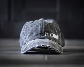 May include: A black distressed denim baseball cap with white embroidery that reads "mama".