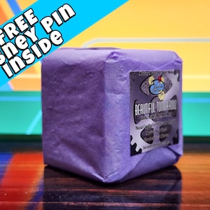 May include: A purple wrapped box with a label that reads "Making Magic for Your Home" and "Beautiful Tomorrow" with a hand-crafted soap inside. The box is sitting on a wooden surface.