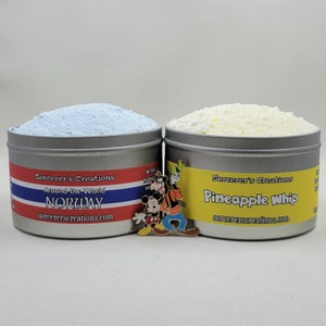 May include: Two silver tins with lids containing bath salts. The tin on the left is blue and says "Sorcerer's Creations Around the World NORWAY sorcererscreations.com". The tin on the right is yellow and says "Sorcerer's Creations Pineapple Whip sorcererscreations.com". A Mickey Mouse and Goofy pin is in front of the tins.