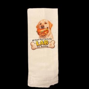 May include: White kitchen towel featuring a smiling yellow Labrador Retriever holding a hamburger. The towel has the text "All Food Must Go to the LAB for Testing" in a playful font, with a bone graphic.