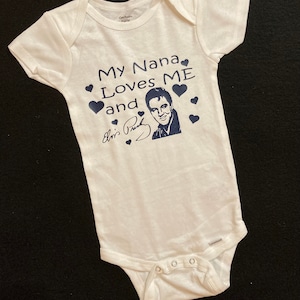 May include: White baby onesie with a blue graphic that says "My Nana Loves Me and Elvis Presley" with a picture of Elvis Presley and a signature.