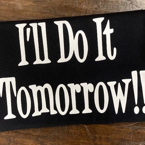以下が含まれることがあります： 「I'll Do It Tomorrow!」という白い文字が書かれた黒いTシャツ