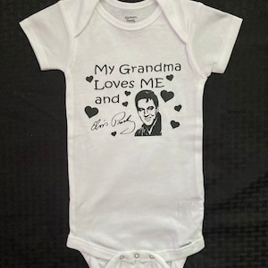 May include: White baby onesie with black text that reads "My Grandma Loves ME and Elvis Presley" with a black and white image of Elvis Presley and black hearts.