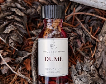 May include: A small clear glass bottle filled with deep red liquid and botanical pieces, topped with a black ribbed cap. The white label reads CONJURED MOON, DUME, RITUAL OIL, and 0.5 FL OZ/15 ML, featuring a crescent moon and star graphic.