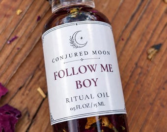 May include: A clear glass bottle with a black screw cap containing a dark liquid with visible botanical pieces. The white label features a crescent moon icon, the text CONJURED MOON, FOLLOW ME BOY, RITUAL OIL, and 0.5 FL OZ / 15 ML.