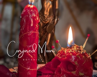 Könnte beinhalten: Zwei rote Kerzen, eine in Form eines Schädels mit Stecknadeln und die andere eine traditionelle Kerze, brennen auf einem Teller mit Rosenblättern. Der Text "Conjured Moon Botanica" ist im Bild sichtbar.