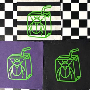 Può includere: Tre toppe da stirare con un disegno a linea verde di una scatola di succo con una cannuccia e uno scarabeo all'interno. Le toppe sono su sfondi di tessuto di diversi colori: a strisce bianche e nere, viola e nero.
