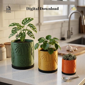 以下が含まれることがあります： 緑、黄色、オレンジ色の3つの装飾的なプランター。それぞれに葉の模様があります。プランターには緑色の植物と多肉植物が入っています。「Digital Download」という文字が画像にあります。