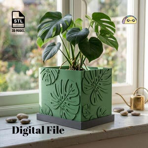 May include: A square green planter featuring embossed monstera leaf patterns on its sides, resting on a dark gray square base. The planter holds a green monstera plant with large, split leaves. The image includes text reading STL 3D MODEL and Digital File.