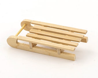 May include: A small, wooden sled with a classic design. The sled features a curved front, runners, and a slatted seat. The natural wood color gives it a rustic look. Perfect for miniature displays or holiday decor.