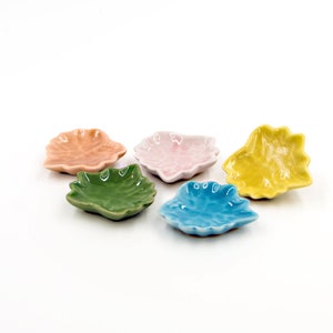 Könnte beinhalten: Fünf kleine Keramik-Schalen in Form von Blättern. Die Schalen sind in verschiedenen Farben: rosa, grün, blau, gelb und orange.