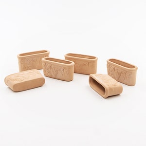 Puede incluir: Seis macetas de terracota con un diseño decorativo. Las macetas son todas del mismo tamaño y forma, y están dispuestas en una fila.