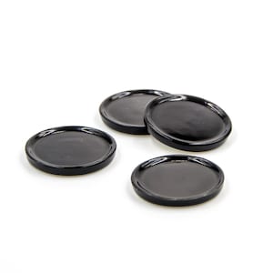 Op de afbeelding: Vier ronde zwarte keramische onderzetters.
