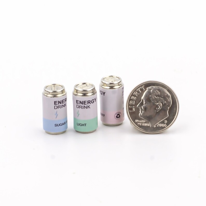 May include: Three miniature aluminum cans with silver tops. The cans are labeled "Energy Drink" with different flavor variations: "Sugar Free", "Light", and "Energy". A silver dime is included for scale.