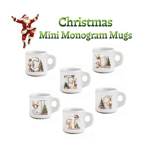 Op de afbeelding: Een verzameling witte mini-monogrammokken met kerstthema-ontwerpen. Elke mok heeft een andere letter, versierd met kerstbomen, rendieren en ornamenten. De afbeelding bevat ook een illustratie van de kerstman en de tekst "Christmas Mini Monogram Mugs."