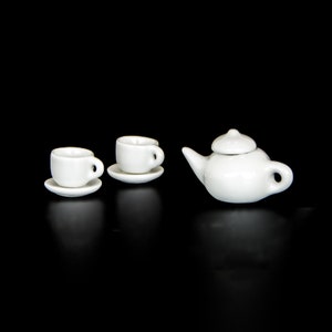 May include: A white tea set with a teapot and two cups and saucers.