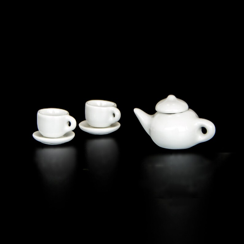 May include: A white tea set with a teapot and two cups and saucers.