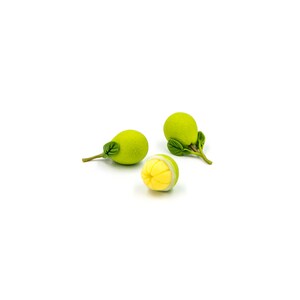 May include: Three green fruit with leaves, one is cut open to reveal a yellow interior.