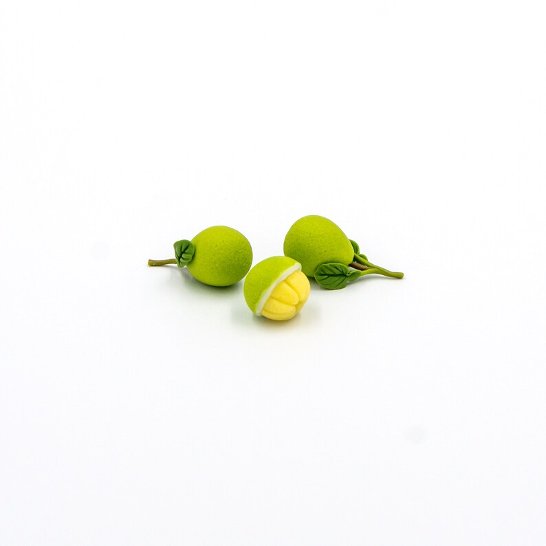 May include: Three green and yellow fruit with leaves on a white background. The fruit is split open to reveal the yellow inside.